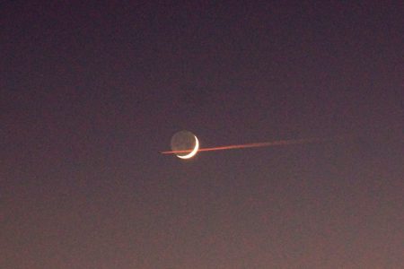 stunning red plane track pass over moon in sky