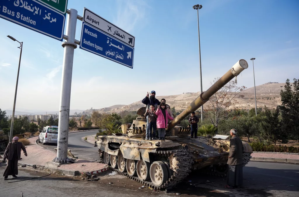 SURİYELİLERDEN ESAD REJİMİNDEN GERİYE KALAN TANKLARIN ÜZERİNDE "ZAFER" POZU ŞAM'DA HALK, TANKLARIN ÜZERİNDE ÖZGÜRLÜĞÜ KUTLUYOR